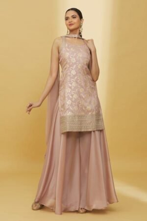 a stylish light mauve Palazzo dress. The sleeveless kurti features an elegant gold floral brocade pattern throughout and a heavily embellished gold border at the hem. It is paired with wide-legged, flowing Palazzo pants in a matching light mauve satin fabric. A sheer light mauve dupatta is draped over her shoulders.