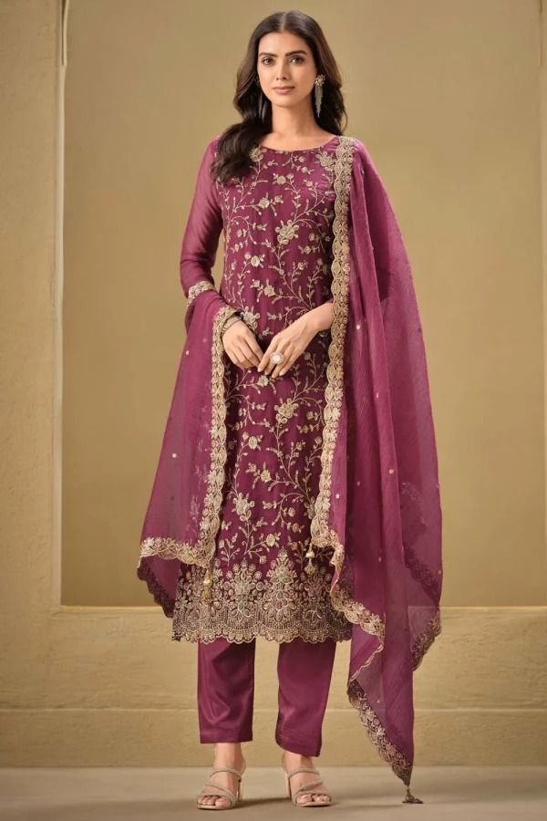 A full-length photo of a woman wearing a maroon Indian salwar kameez suit.